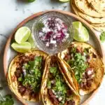 Mexican Street Tacos Recipe Authentic & Juicy Favorite 6 Mexican street tacos with grilled carne asada, fresh cilantro, red onion, and lime wedges on golden corn tortillas, styled on a rustic plate