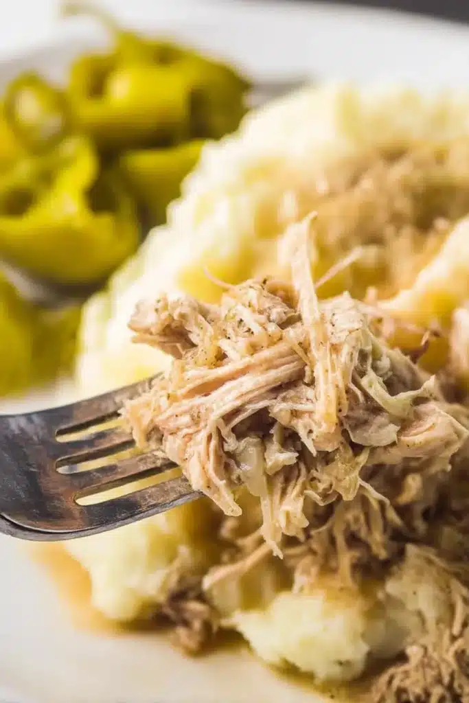 Mississippi Chicken | Easy Tangy Comfort Meal 7 Close-up of shredded Mississippi chicken and mashed potatoes on a fork with pepperoncini