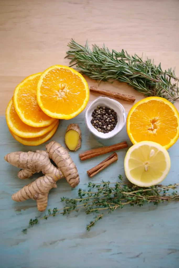 Fire Cider Recipe (Immune-Boosting Herbal Tonic) 7 Optional fire cider ingredients including citrus, turmeric, cinnamon, herbs, and black peppercorns on a light wood surface