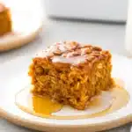 Pumpkin Baked Oatmeal 13 Close-up of moist pumpkin baked oatmeal slice drizzled with syrup on ceramic plate, with rustic cozy background