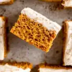 Pumpkin Bars with Cream Cheese Frosting – Quick & Delicious 7 Moist pumpkin bars with cream cheese frosting and cinnamon, one lifted to show soft texture.