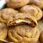 Close-up of pumpkin cheesecake snickerdoodles with a soft, creamy center on a parchment-lined tray