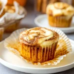 Pumpkin Cream Cheese Swirl Muffins 9 Pumpkin cream cheese swirl muffin on a white plate with creamy swirl and soft moist texture