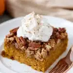 Pumpkin Crunch Cake | Easy Fall Favorite Dessert 9 Slice of pumpkin crunch cake with whipped cream and pecan topping on a white plate