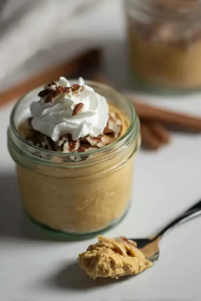Fluffy pumpkin fluff dessert in a jar with pecans and whipped cream topping

