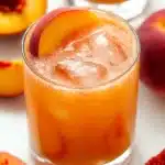 Amazing Fresh Peach Margaritas Recipe | Quick & Refreshing 12 Fresh Peach Margaritas served in a glass with ice, peach garnish, and sliced peaches on a pale wood background
