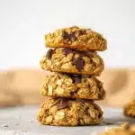 Stack of four rustic pumpkin oat cookies with oats and chocolate chips on a light background.