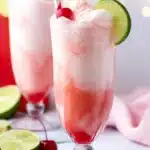 Shirley Temple Ice Cream Float: Sweet, Fizzy, and Fun 9 Shirley Temple ice cream float in a tall glass with pink soda, vanilla ice cream, cherry and lime garnish