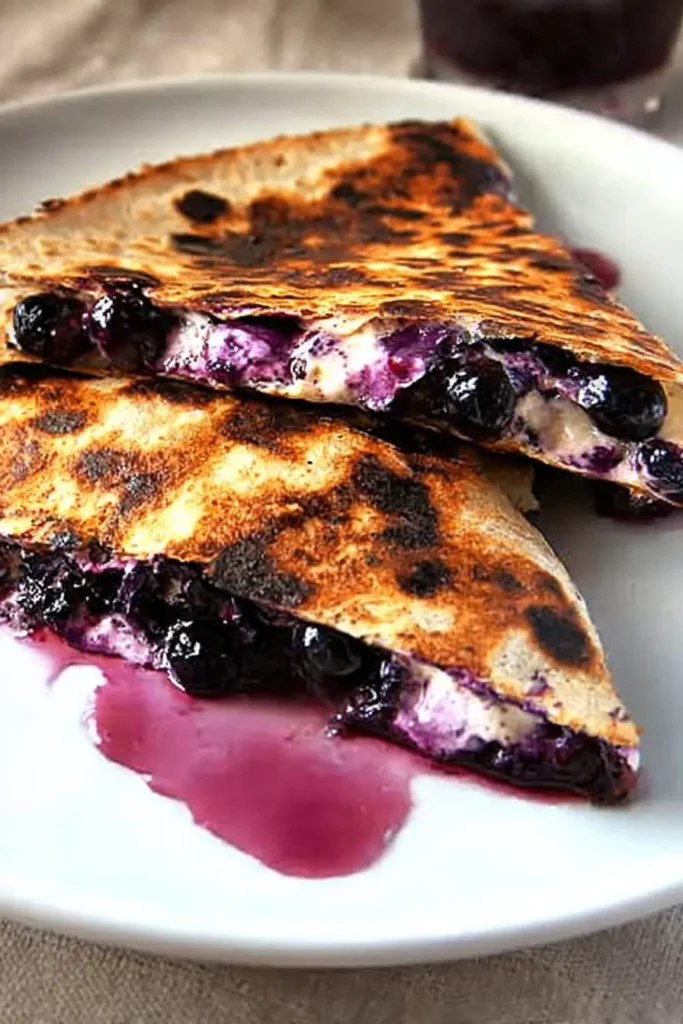 Blueberry Breakfast Quesadilla | Quick & Tasty Morning Win 8 Sliced blueberry breakfast quesadilla with juicy filling and berry stains on white plate