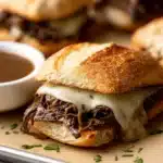 Crockpot French Dip Sandwiches with shredded beef, melted cheese, and au jus on crusty rolls