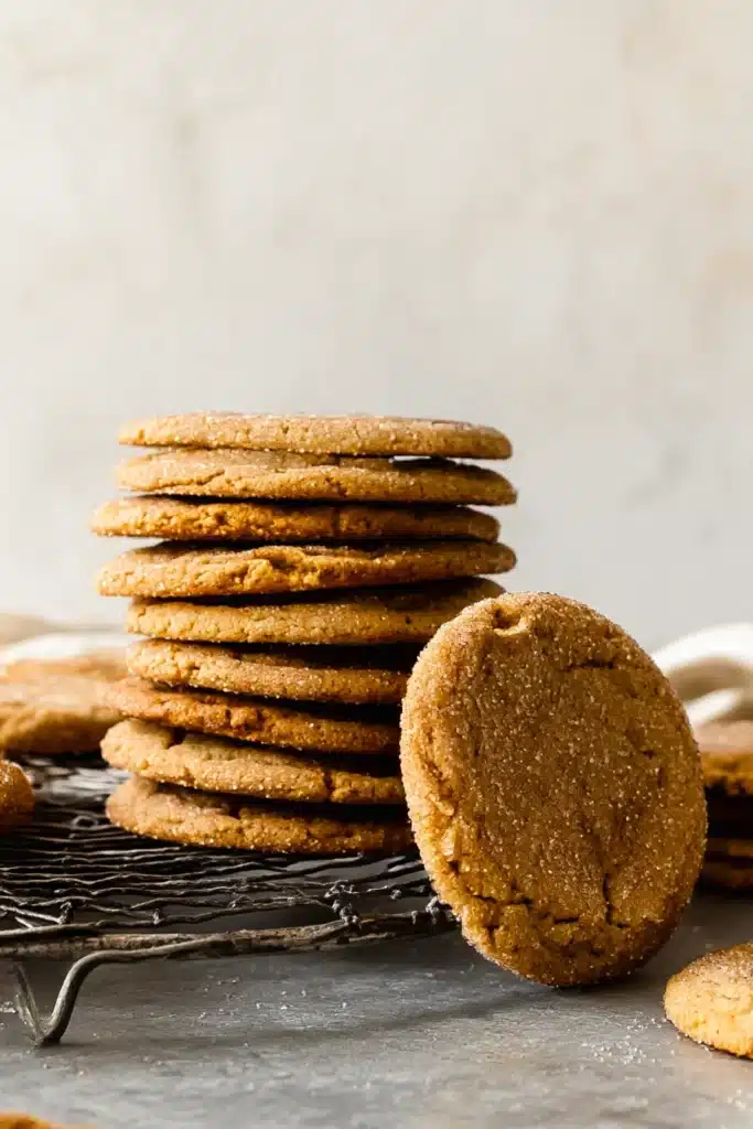 Stack of chewy maple pumpkin cookies cooling on a wire rack with sugar-dusted tops and crisp edges.