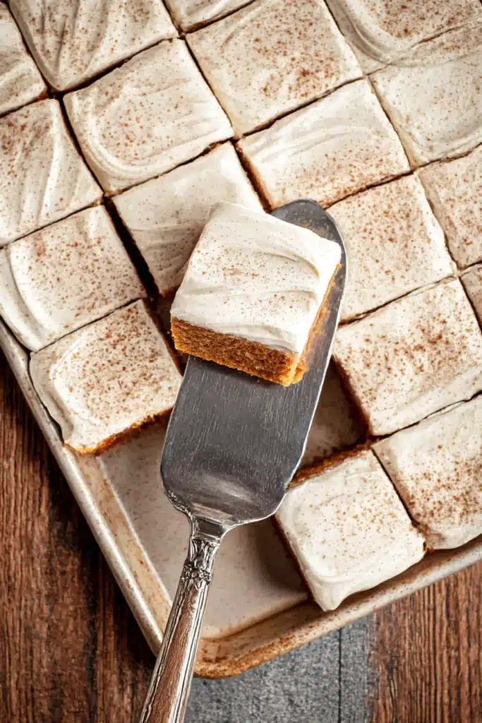Pumpkin Bars with Cream Cheese Frosting – Quick & Delicious 6 Tray of sliced pumpkin bars with cream cheese frosting, one lifted on vintage silver spatula.