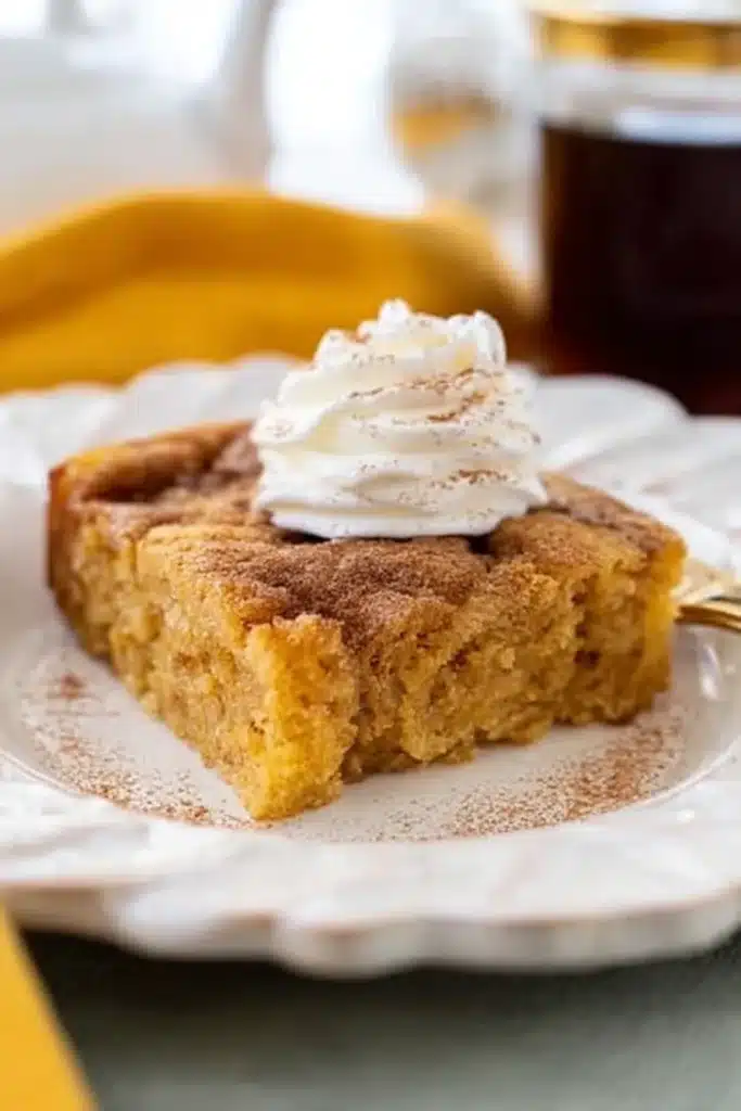 Single slice of keto pumpkin cake with cinnamon and whipped cream on a decorative plate