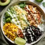 Amazing Slow Cooker Chicken Burrito Bowl Packed with Flavor 6 Slow Cooker Chicken Burrito Bowl with shredded chicken, rice, corn, black beans, avocado, cheese, cilantro, and lime in a white bowl