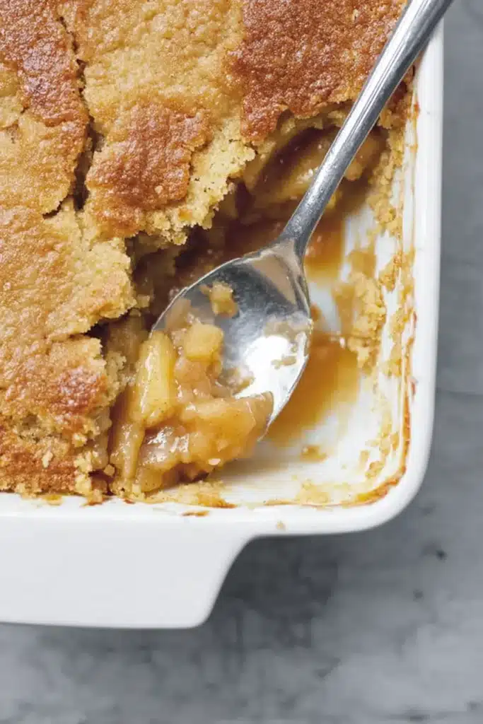 3-Ingredient Apple Dump Cake in a white baking dish with spoon