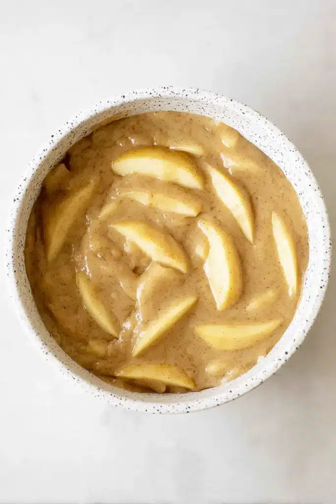 Easy Cinnamon Apple Cake batter with sliced apples in ceramic bowl