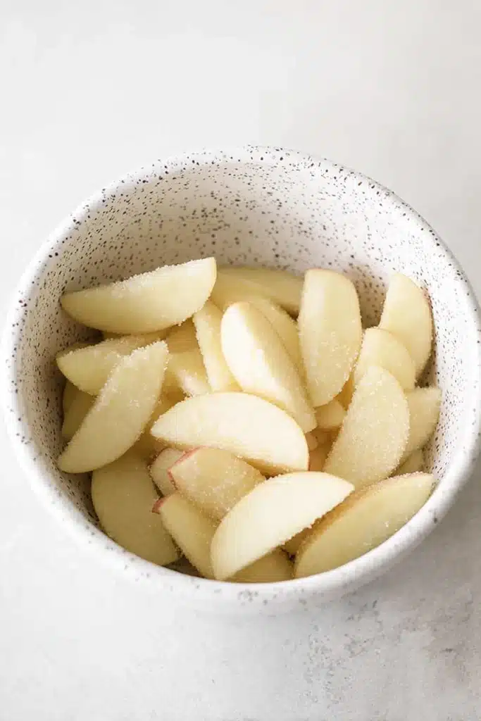 Easy Cinnamon Apple Cake apple slices tossed with sugar in ceramic bowl