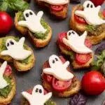 Caprese Crostini Ghosts – Spooky & Easy Halloween Fun 5 Caprese Crostini Ghosts with mozzarella ghosts, pesto, and tomatoes on a Halloween appetizer platter