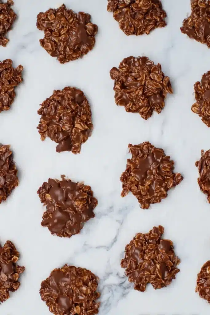 Chocolate No Bake Cookies – Quick, Easy & Delicious 9 Overhead view of chocolate no bake cookies cooling on a white parchment surface in even rows