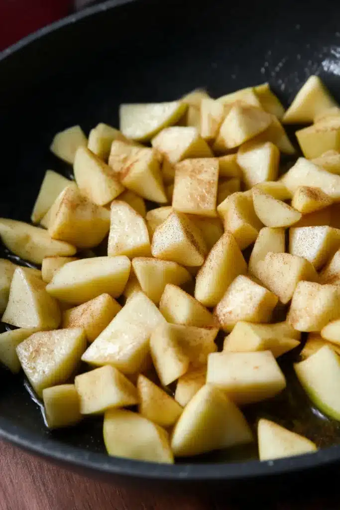 Chopped apples with cinnamon in a black skillet for healthy breakfast crumble

