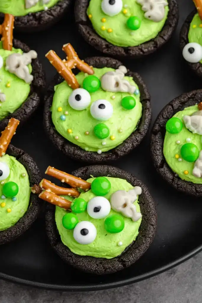 Easy Cauldron Cookies – Fun & Spooky Halloween Treat 9 Easy Cauldron Cookies with green frosting, candy eyes, skull sprinkles, and pretzel sticks