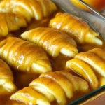 Easy Apple Dumplings – Quick, Cozy & Delicious 7 Easy apple dumplings recipe with crescent roll dough and cinnamon sugar syrup, shown unbaked in a glass dish.