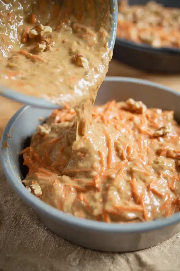 Pouring easy carrot cake batter into a round baking pan