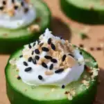 Everything Bagel Cucumber Bites topped with whipped cream cheese on a wooden board