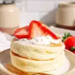 Fluffy Japanese Soufflé Pancakes – Soft & Jiggly Delight 10 Stack of fluffy Japanese soufflé pancakes with strawberries and whipped cream