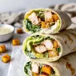 Chicken Caesar Wrap – Quick & Delicious Lunch Recipe 6 Close-up of stacked chicken Caesar wraps with lettuce, chicken, croutons, parmesan, and creamy dressing on a tortilla.