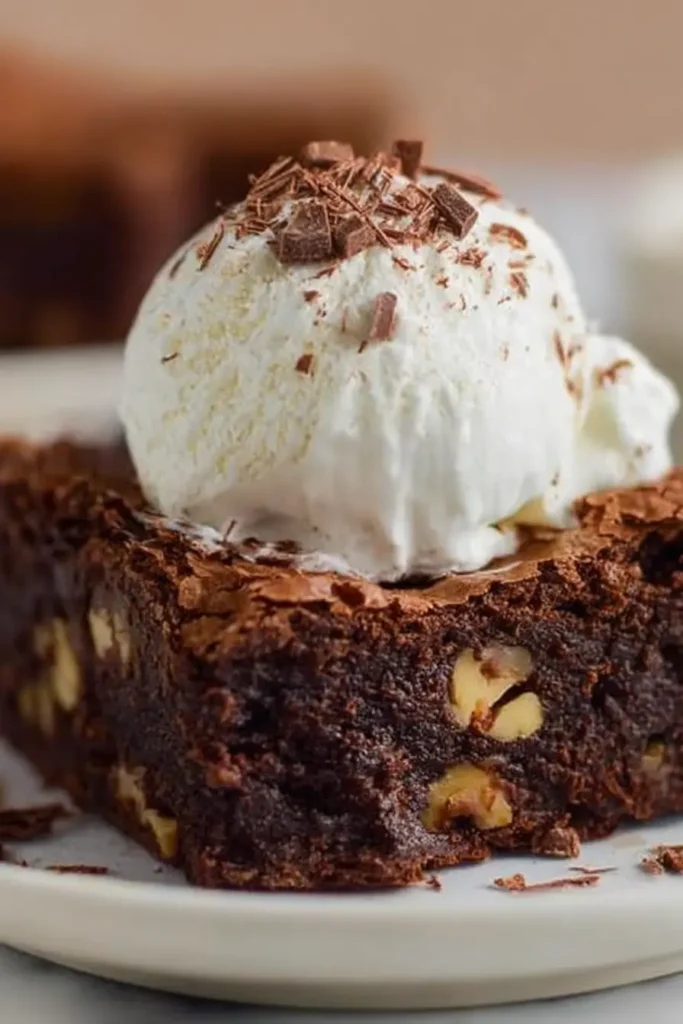 Fudgy homemade brownie topped with vanilla ice cream and chocolate shavings