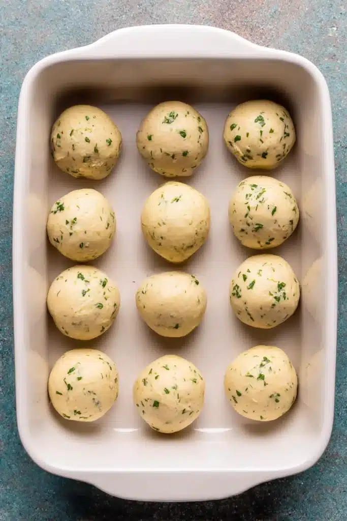 Garlic Butter Bread Rolls (Soft, Fluffy & Flavor-Packed) 14 Unbaked garlic herb dinner rolls arranged in a white ceramic dish before baking