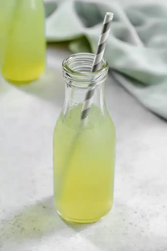 Simple Green Apple Soda with Homemade Juice in a glass bottle with striped straw