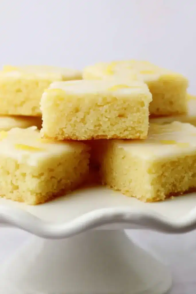 Lemon brownies with glaze arranged on a white cake stand