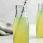 Simple Green Apple Soda with Homemade Juice in a clear glass bottle with striped straw