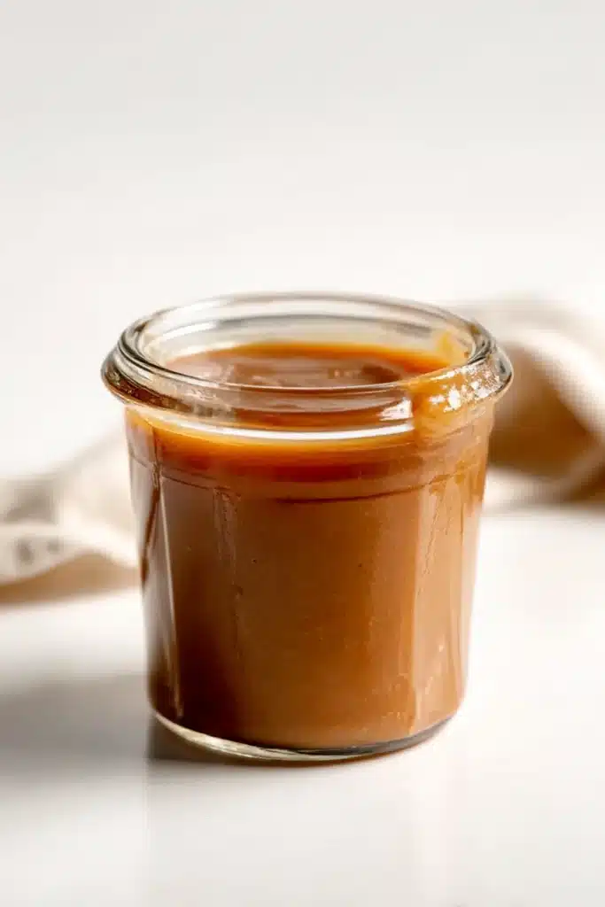 Slow Cooker Apple Butter – Easy & Delicious Recipe 21 Simple glass jar filled with homemade apple butter on a white table.