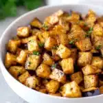 Crispy low-calorie air fryer eggplant cubes in a white bowl with fresh herbs
