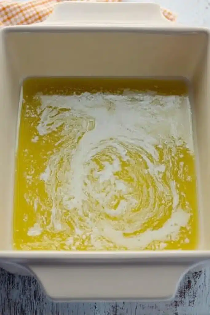 Melted butter in a ceramic dish for making magic lemon cobbler