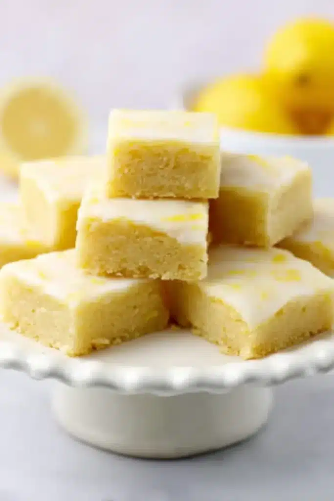 Lemon Brownies Recipe – Sweet, Tangy & Irresistible Treat 7 Soft lemon brownies with glaze on a white cake stand