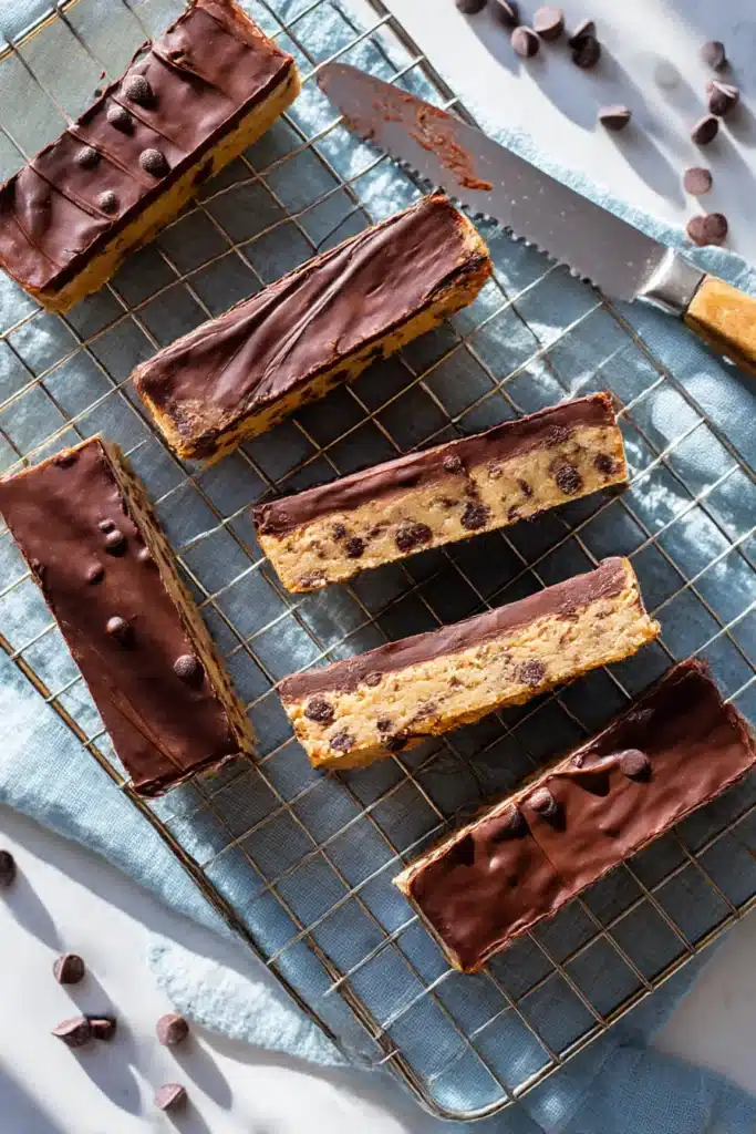 No-Bake Cookie Dough Bars – Simple & Delicious Treat 6 No bake cookie dough bars arranged on parchment with knife and cooling rack