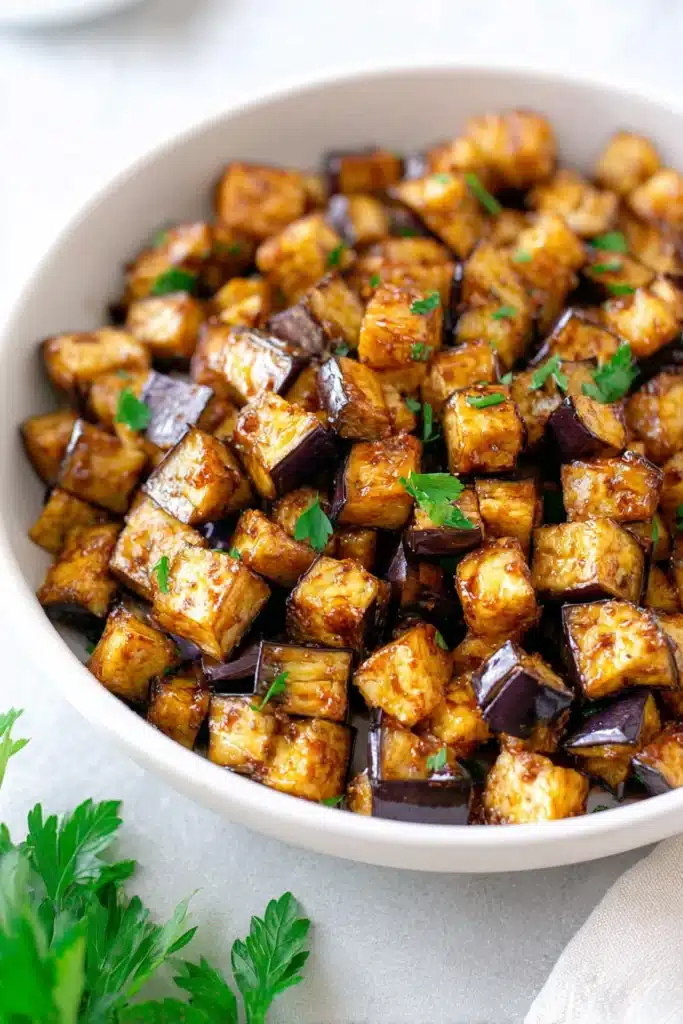 Overhead view of low-calorie air fryer eggplant in white bowl with parsley