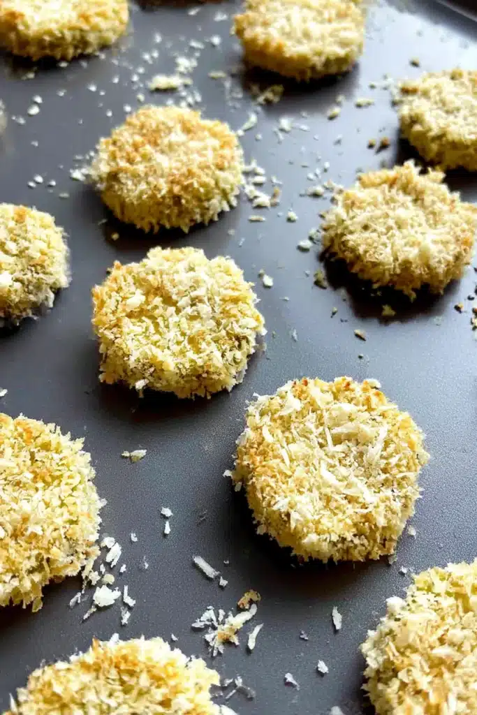 Panko breaded pickle slices on gray baking tray ready for air frying