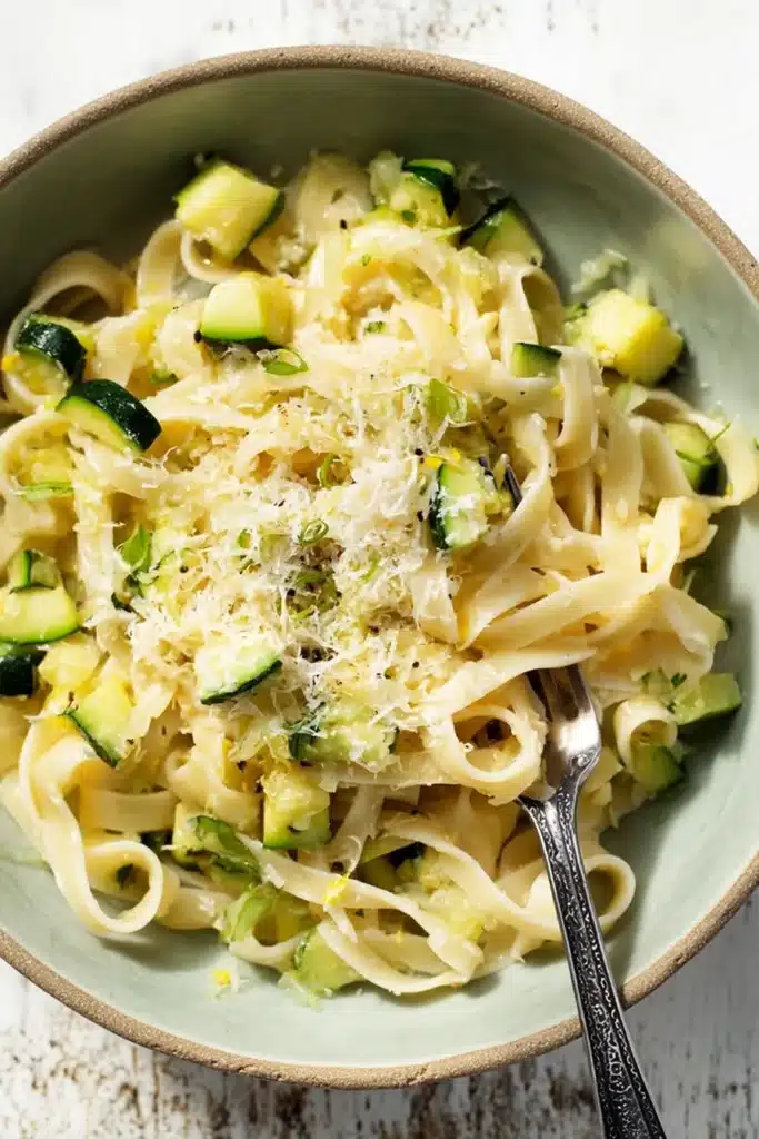 Fettuccine pasta with zucchini lemon garlic sauce and parmesan in a rustic ceramic bowl