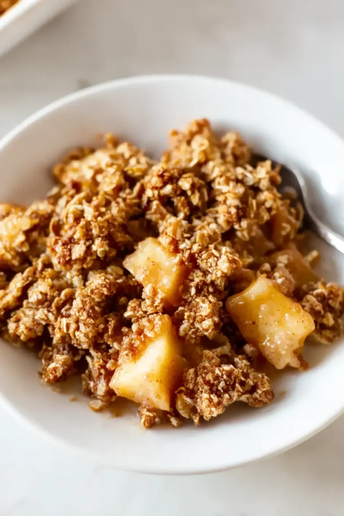 Healthy breakfast apple crumble served on a white plate with golden topping