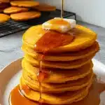 Stack of golden pumpkin cottage cheese pancakes with butter and maple syrup