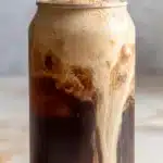 Pumpkin cream cold brew coffee in clear glass with creamy swirl