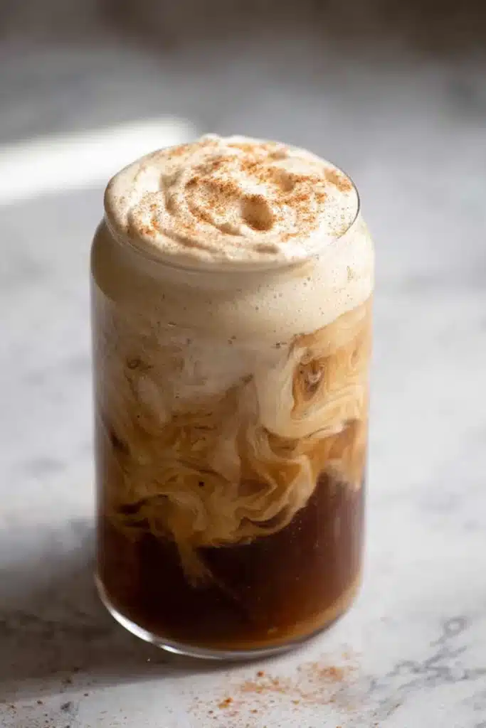 Pumpkin cream cold brew topped with cinnamon foam in a clear glass