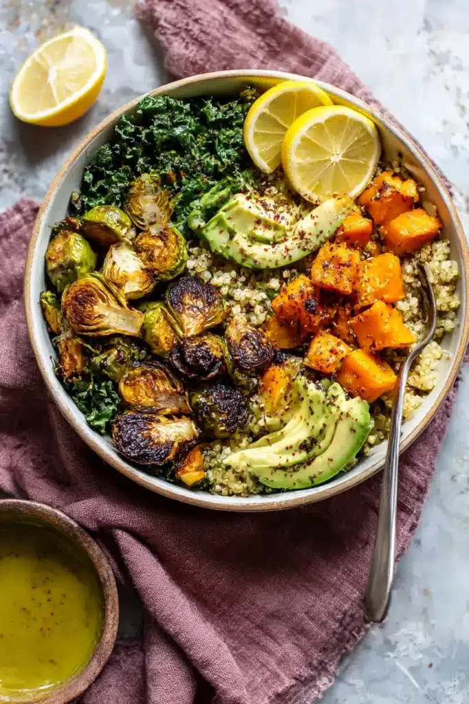 Quinoa and Veggie Power Bowls in white bowl with avocado, roasted Brussels sprouts, squash, and lemon