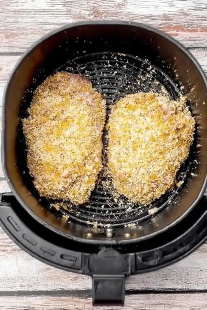 Uncooked panko chicken thighs in air fryer basket ready to cook