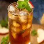 Tall glass of refreshing apple iced tea with mint and apple garnish